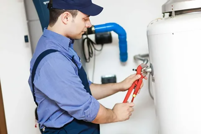 A professional technician performing maintenance on a tank water heater in a residential setting, highlighting the company's comprehensive services for effective operation in both homes and businesses.