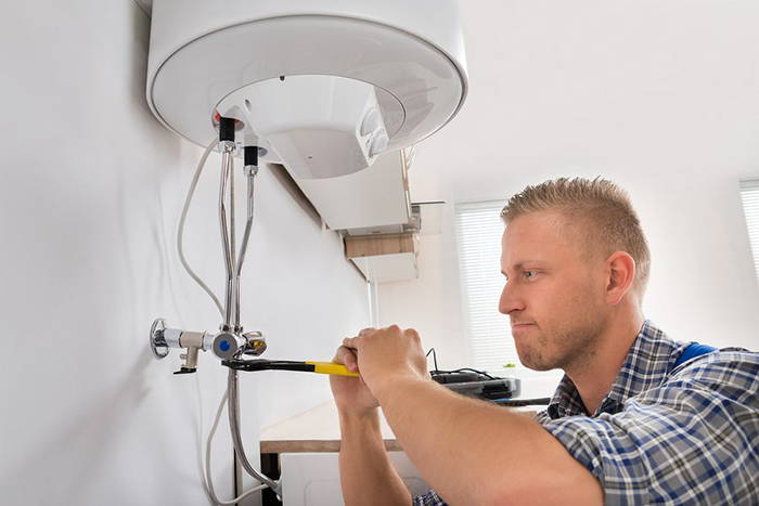 A technician performing maintenance on a tankless water heater, emphasizing regular descaling and flushing to prevent mineral buildup. The image highlights Water Heater Repair McKinney, TX’s commitment to cost-effective installation, reliable repairs, and long-lasting solutions for residential and commercial clients.

            